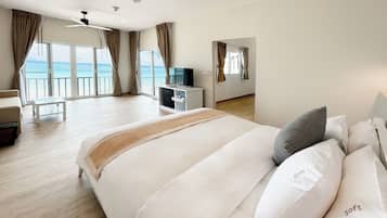 Une chambre d’hôtel spacieuse, dotée d’un grand lit, d’un bureau avec une télévision et d’un balcon offrant une vue sur la mer.