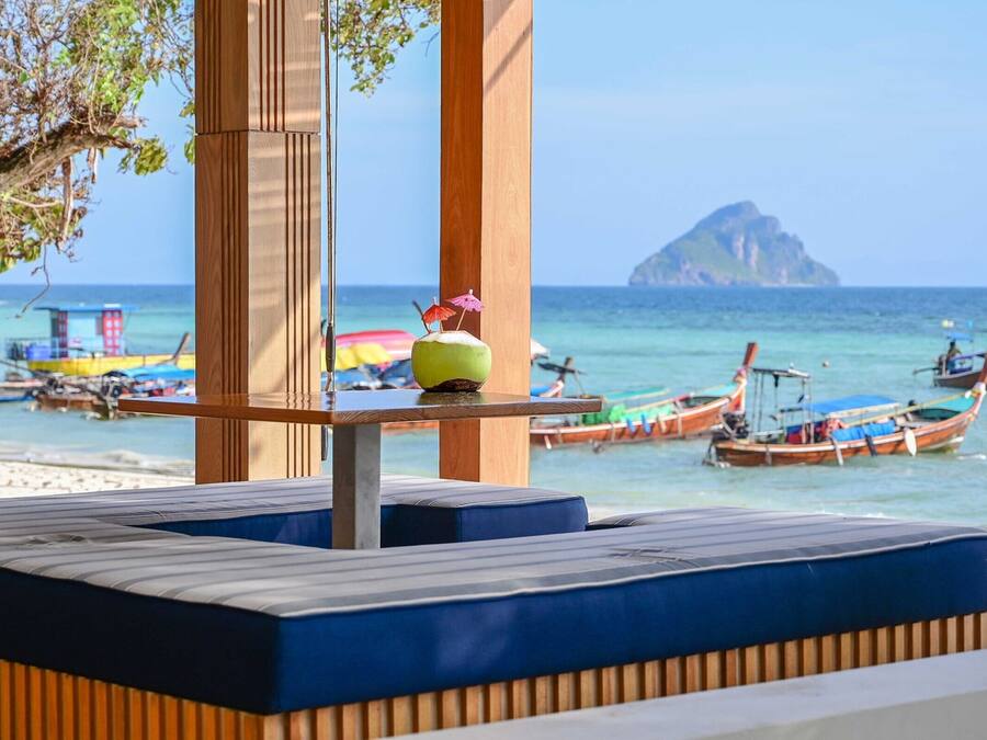 Ein Sitzbereich am Strand mit Blick auf das Meer und Boote.