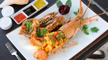Un plato de mariscos con una fuente blanca, dos recipientes pequeños de salsa y un tenedor sobre una mesa.