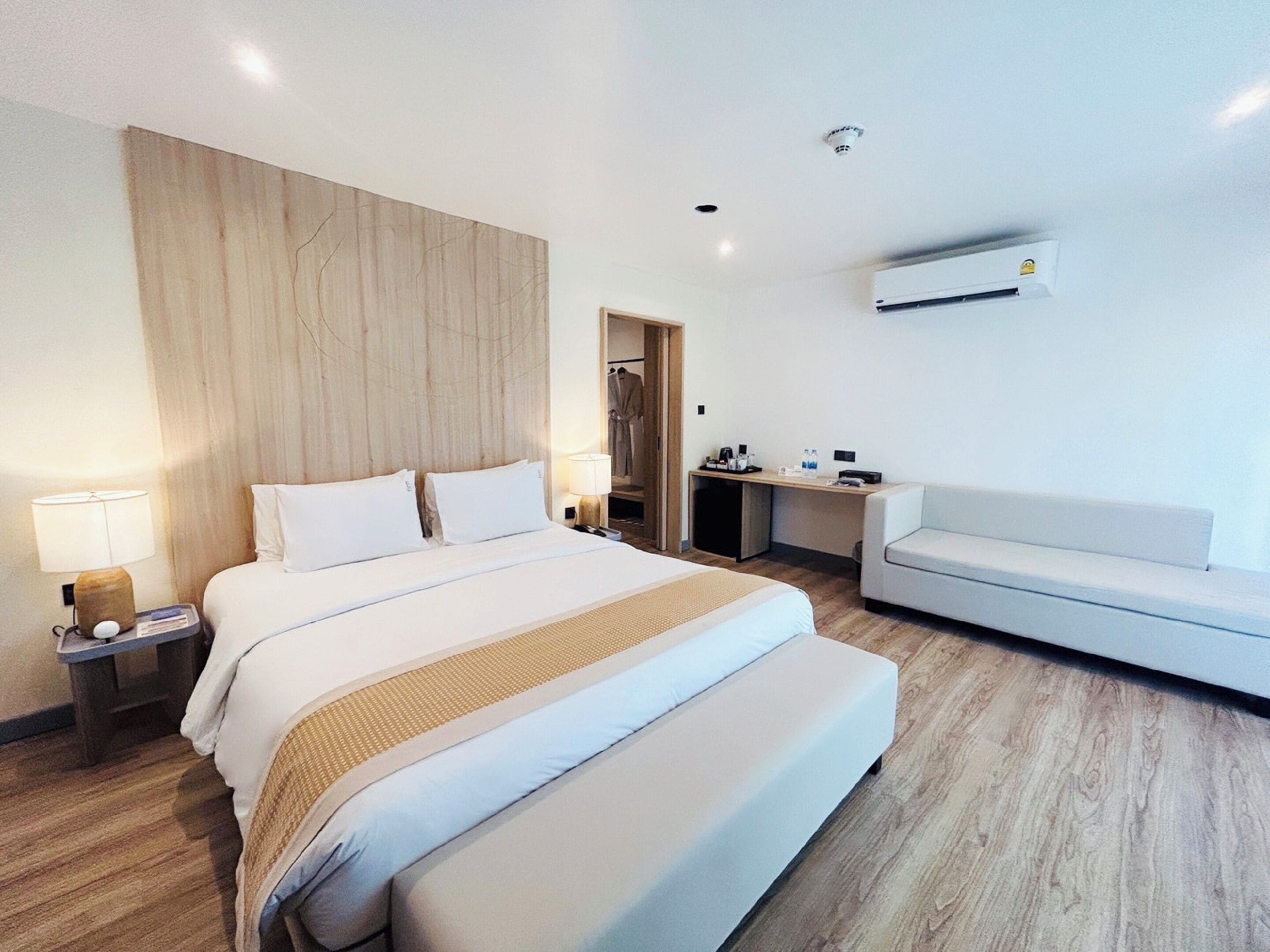 Habitación de hotel moderna con una cama grande, un escritorio, un sofá y un equipo de aire acondicionado.