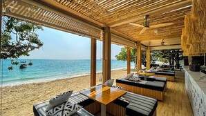 Un restaurante frente al mar con vigas de madera, asientos a rayas y vistas al océano.