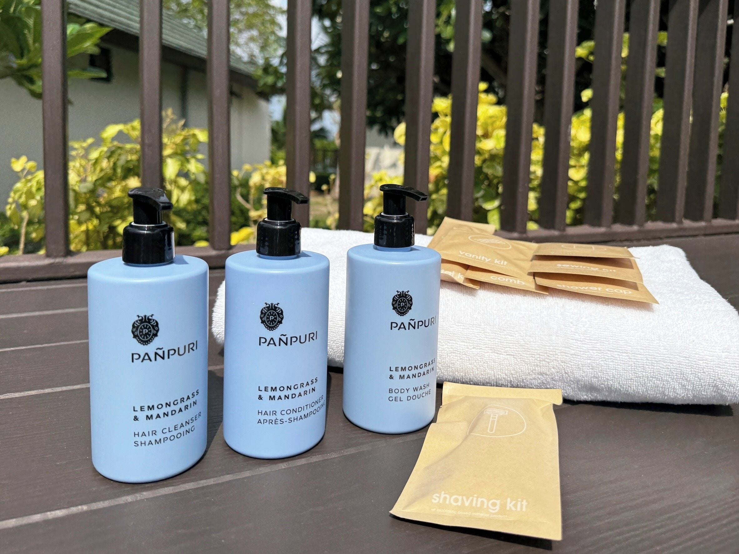 Three bottles of Panpuri hair care products, a towel, and a shaving kit on a table.