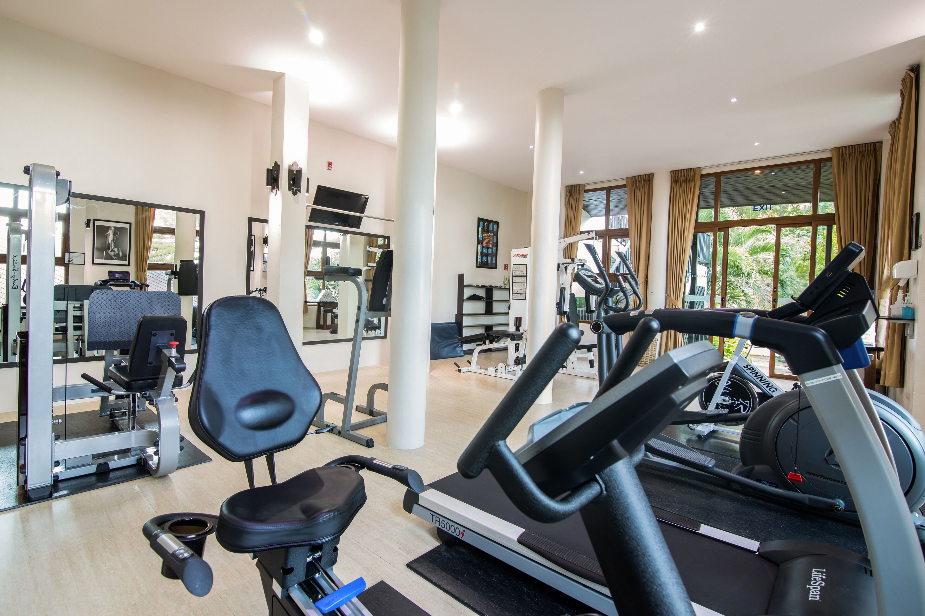 A gym with cardio equipment, weight machines, and a mirror.