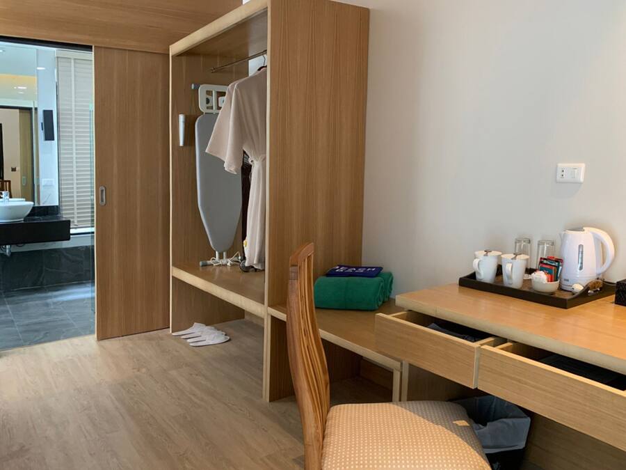 Habitación de hotel moderna con un armario de madera, un escritorio con una bandeja de desayuno, una silla y vistas al baño.
