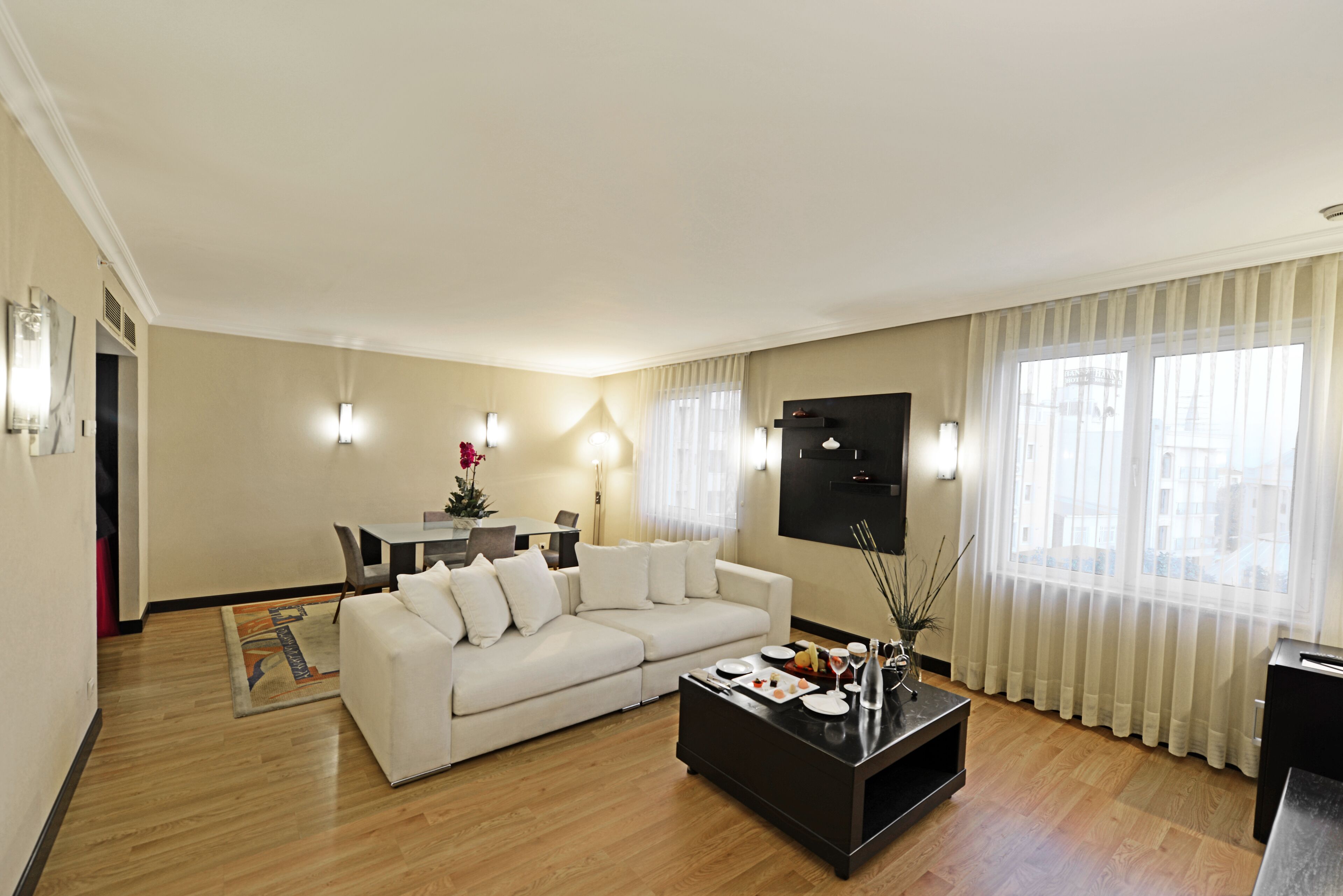 Een moderne woonkamer met een witte bank, een salontafel en een eethoek op de achtergrond.