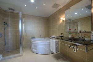 Ein modernes Badezimmer mit barrierefreier Dusche, freistehender Badewanne, Waschtisch und großem Spiegel.