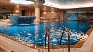 An indoor swimming pool with a waterfall feature, surrounded by a tiled deck and a mural depicting a coastal scene. - Eresin Hotels Topkapi (Istanbul)