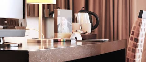 Une chambre d’hôtel équipée d’un bureau, d’une lampe, d’une chaise, d’une machine à café et d’un téléviseur.