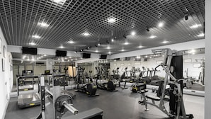 Un gimnasio moderno con diversos equipos de ejercicio, como cintas de correr, elípticas y máquinas de pesas.