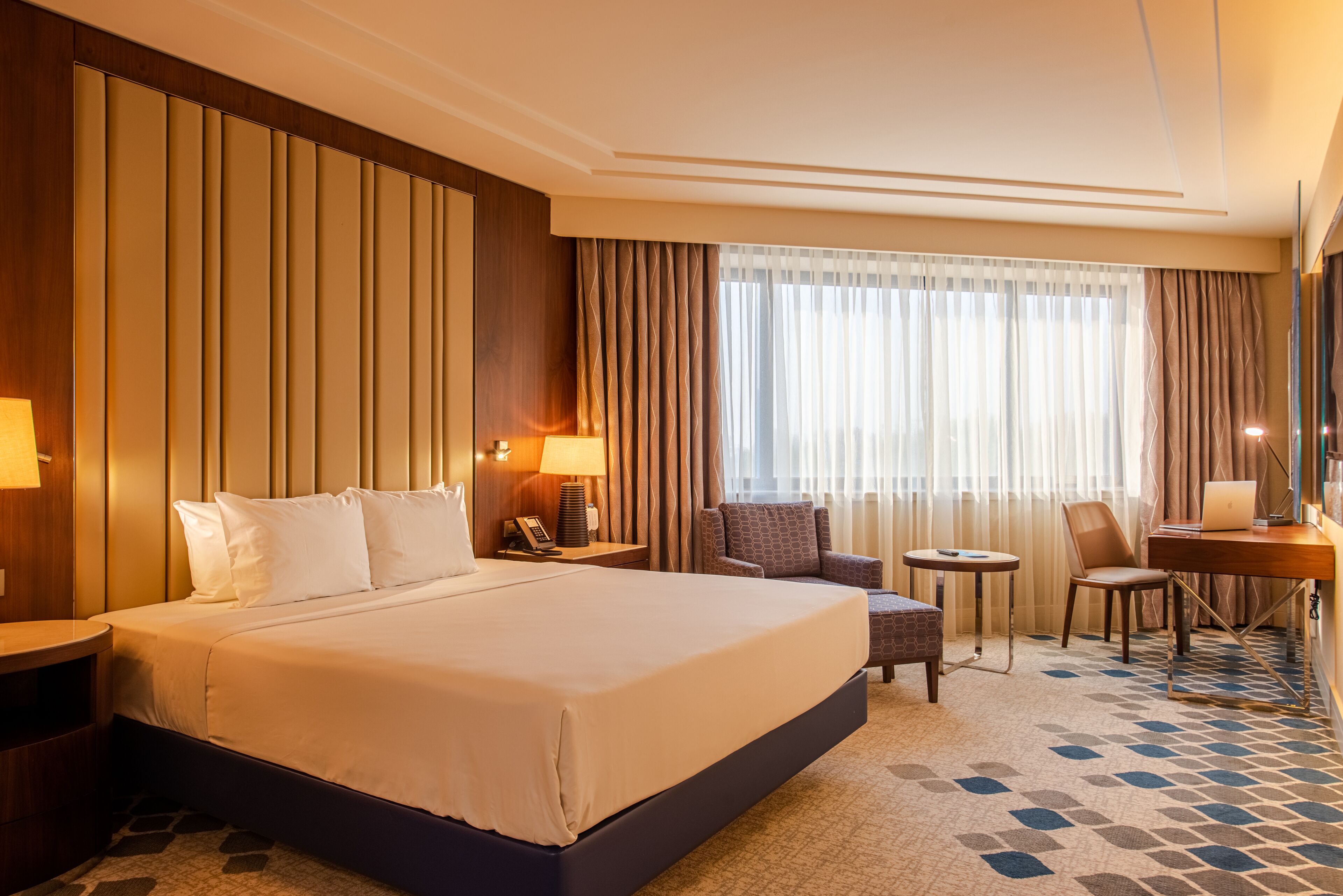Une chambre d’hôtel avec un grand lit, un bureau, une chaise et une petite table.