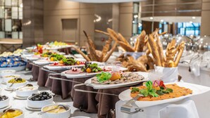 Un bufé con diversos platos y pan, dispuesto en mesas en un ambiente moderno.