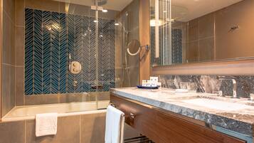 A modern bathroom with a glass-enclosed shower, a bathtub, and a vanity with a marble countertop.