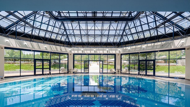 Una gran piscina interior con techo de vidrio y ventanas amplias.