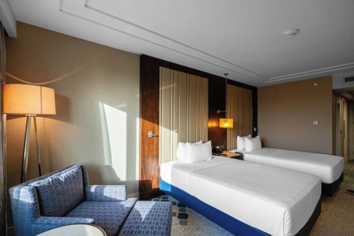 A hotel room with a bed, a sofa, a lamp, and a nightstand.