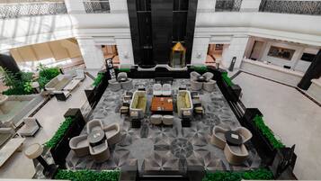 Un hall d’entrée spacieux, aménagé à l’intérieur, avec un espace salon central, une fontaine décorative et un sol à motifs.