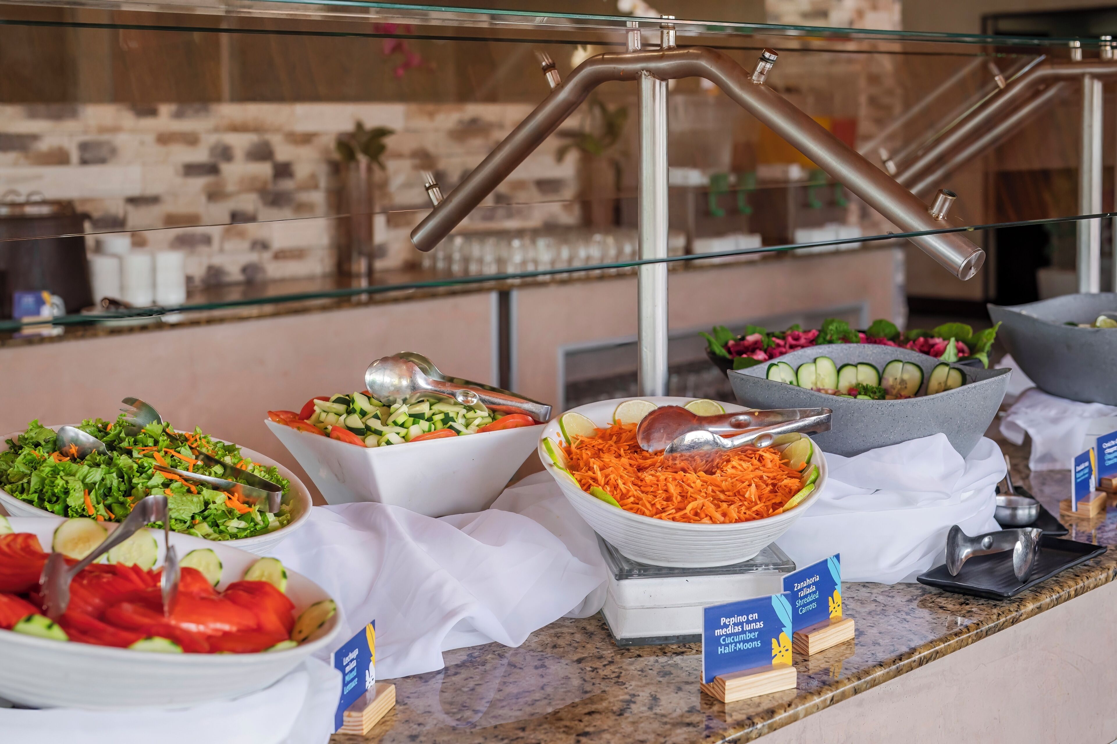 A buffet with various salads and fruits, a scale for weighing food, and a sign indicating the availability of a car wash service.