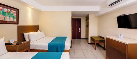 Quarto de hotel com duas camas, uma escrivaninha, uma televisão e um quadro na parede.