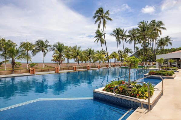 A swimming pool with clear blue water, surrounded by palm trees and a view of the beach. - Best Western Jaco Beach All-Inclusive Resort (Jacó)
