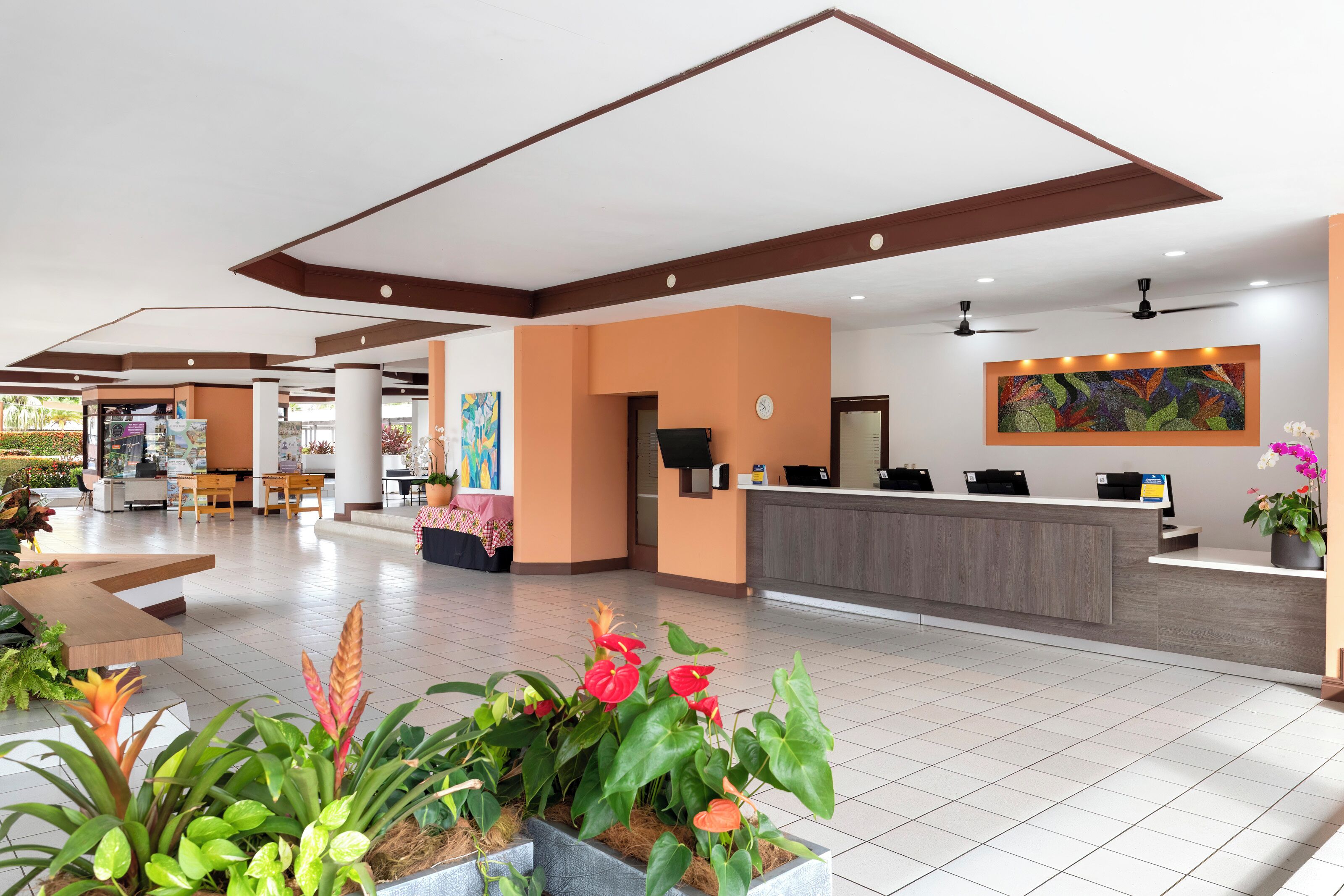 Un hall d’hôtel comprenant un comptoir d’accueil, un espace salon et des plantes d’intérieur.