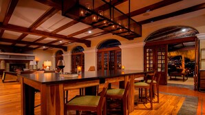 A spacious dining area with a large wooden table and chairs, arched doorways, and a view of the city at night. - Costa Rica Marriott Hotel Hacienda Belen (La Asunción)