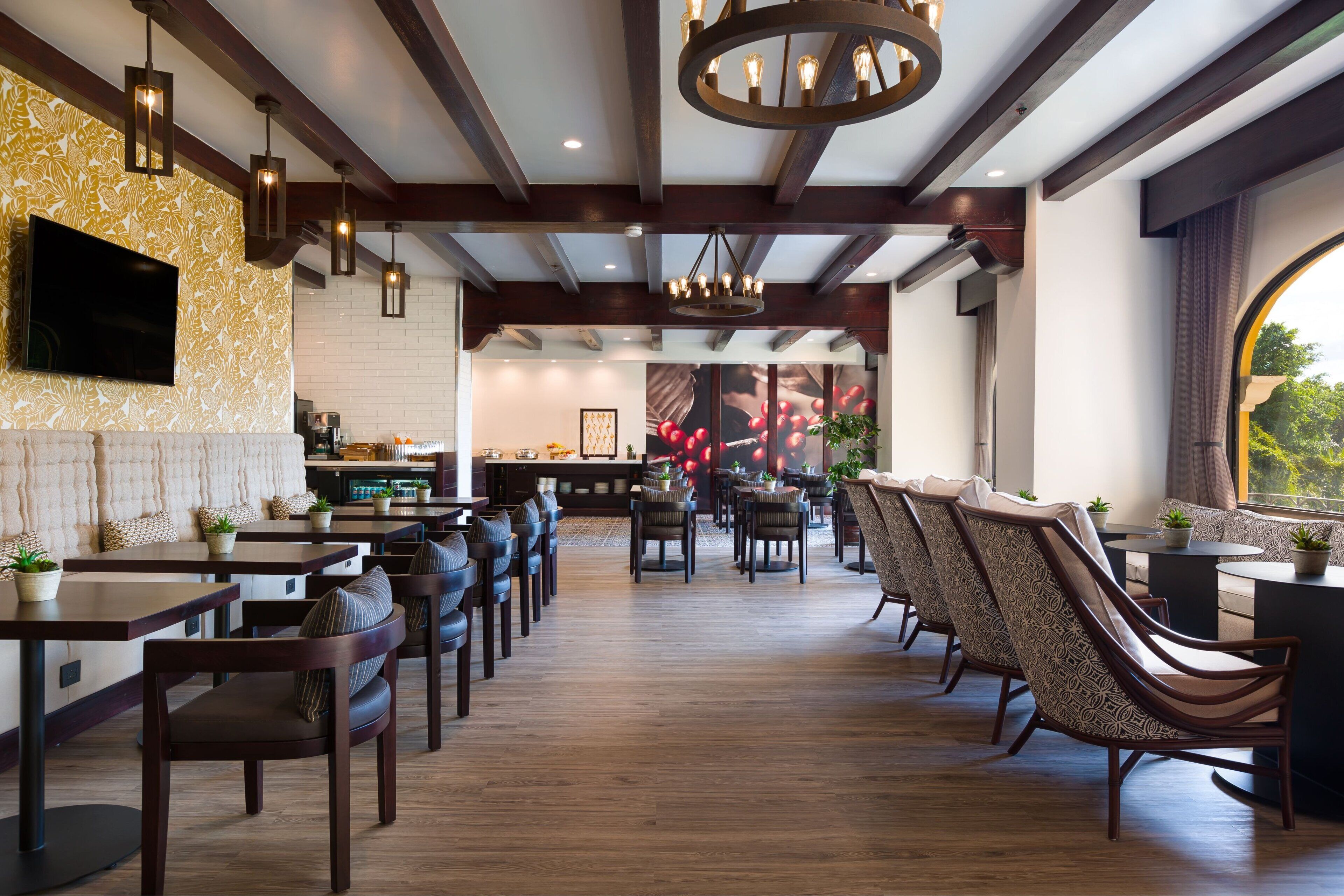 Un ristorante con pavimento in legno, sedie scure e tavoli. È presente una televisione montata a parete e un lampadario appeso al soffitto.