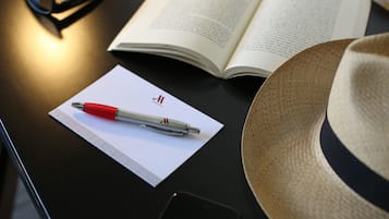 A book, a pen, a smartphone, and a hat on a table.