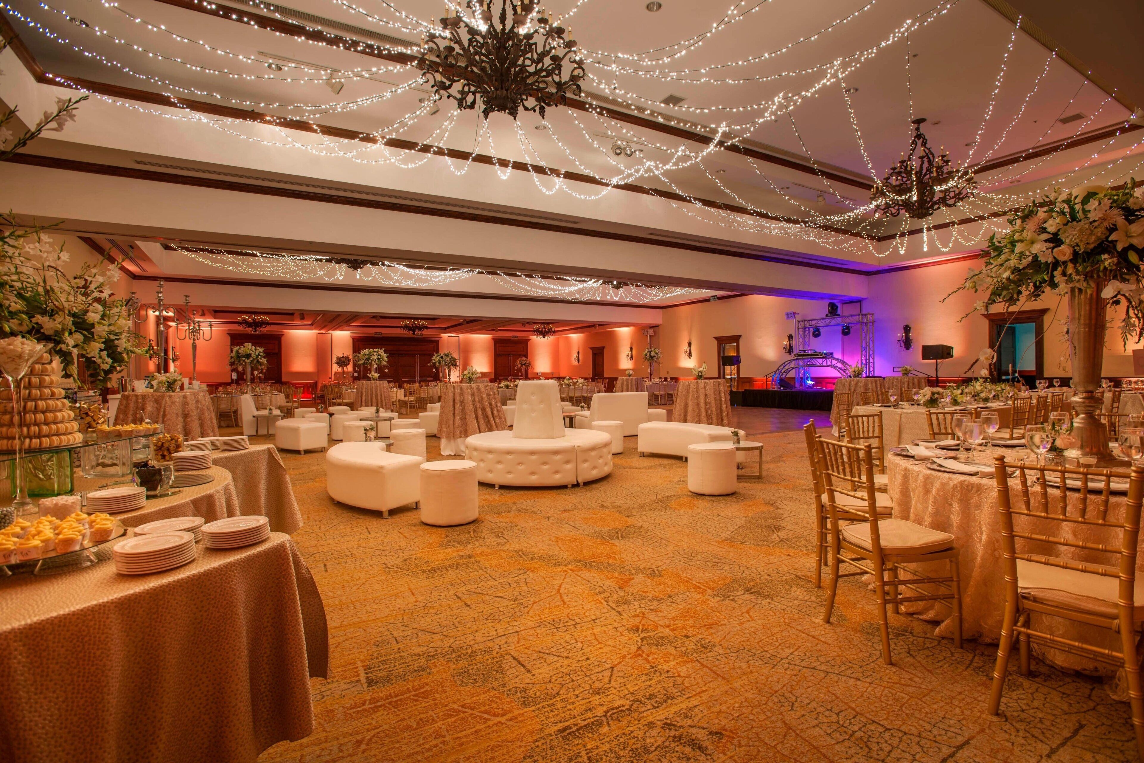 A banquet hall with round tables, white chairs, and a carpeted floor.