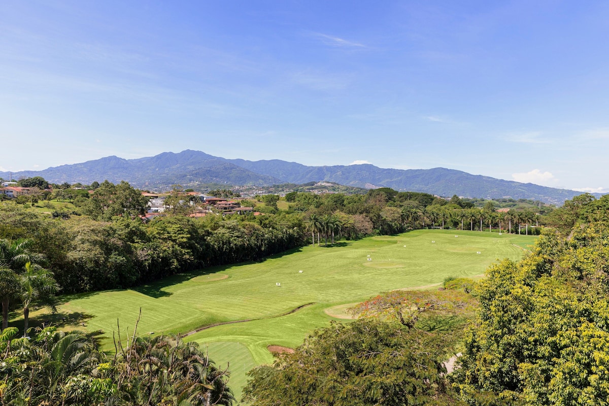 A golf course with a view of mountains and a town in the background.