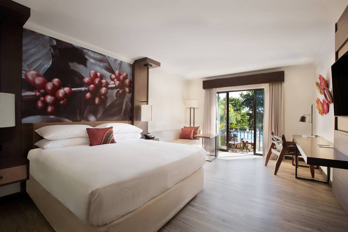 Une chambre d’hôtel avec un grand lit, un bureau et un balcon avec vue.