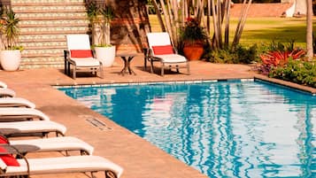 A pool area with lounge chairs and potted plants.