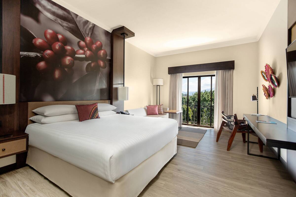 Une chambre d’hôtel moderne avec un grand lit, un bureau et une vue sur l’extérieur.