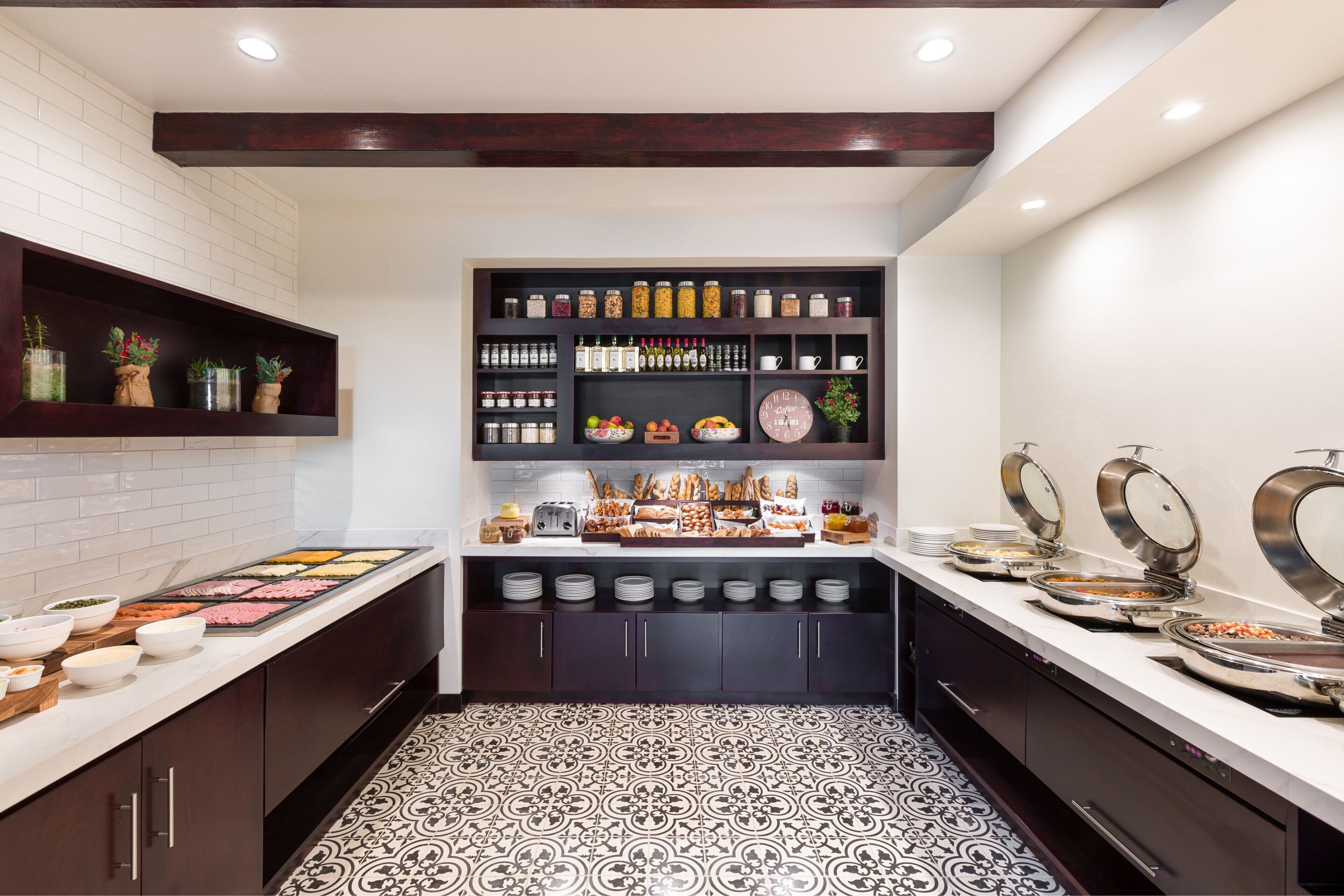 A modern kitchen with a white tiled backsplash, dark wooden cabinets, and a patterned floor.