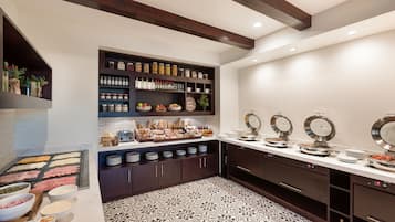 Una cocina moderna con suelo de mármol, armarios de madera oscura y diversos alimentos exhibidos en estantes y encimeras.