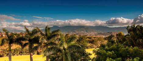 A panoramic view of a mountainous landscape with a clear sky and scattered clouds.