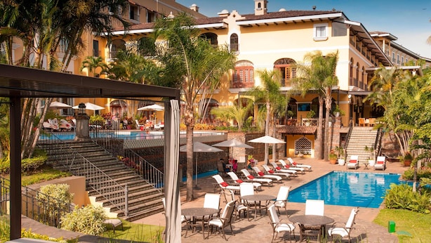 A resort with a swimming pool, lounge chairs, and a staircase leading to a second floor. - Costa Rica Marriott Hotel Hacienda Belen (La Asunción)