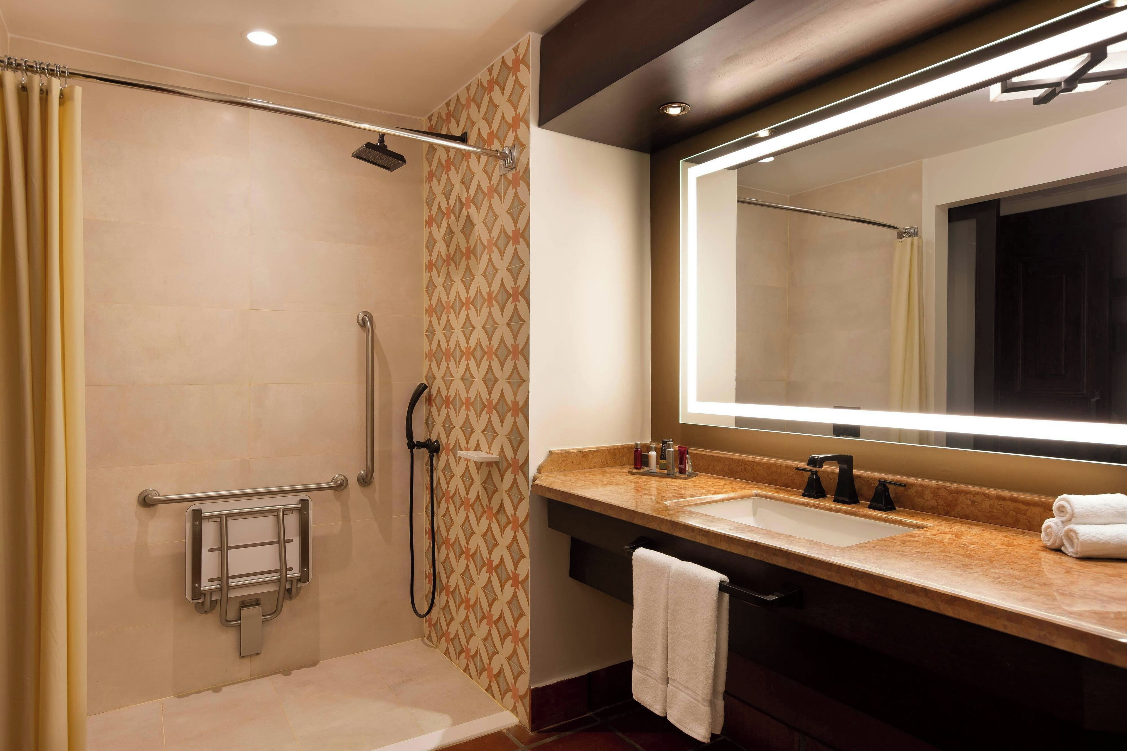 Un baño moderno con cabina de ducha, tocador con un espejo grande y perchero para toallas.