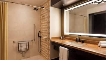 Un baño moderno con cabina de ducha, tocador con un espejo grande y perchero para toallas.