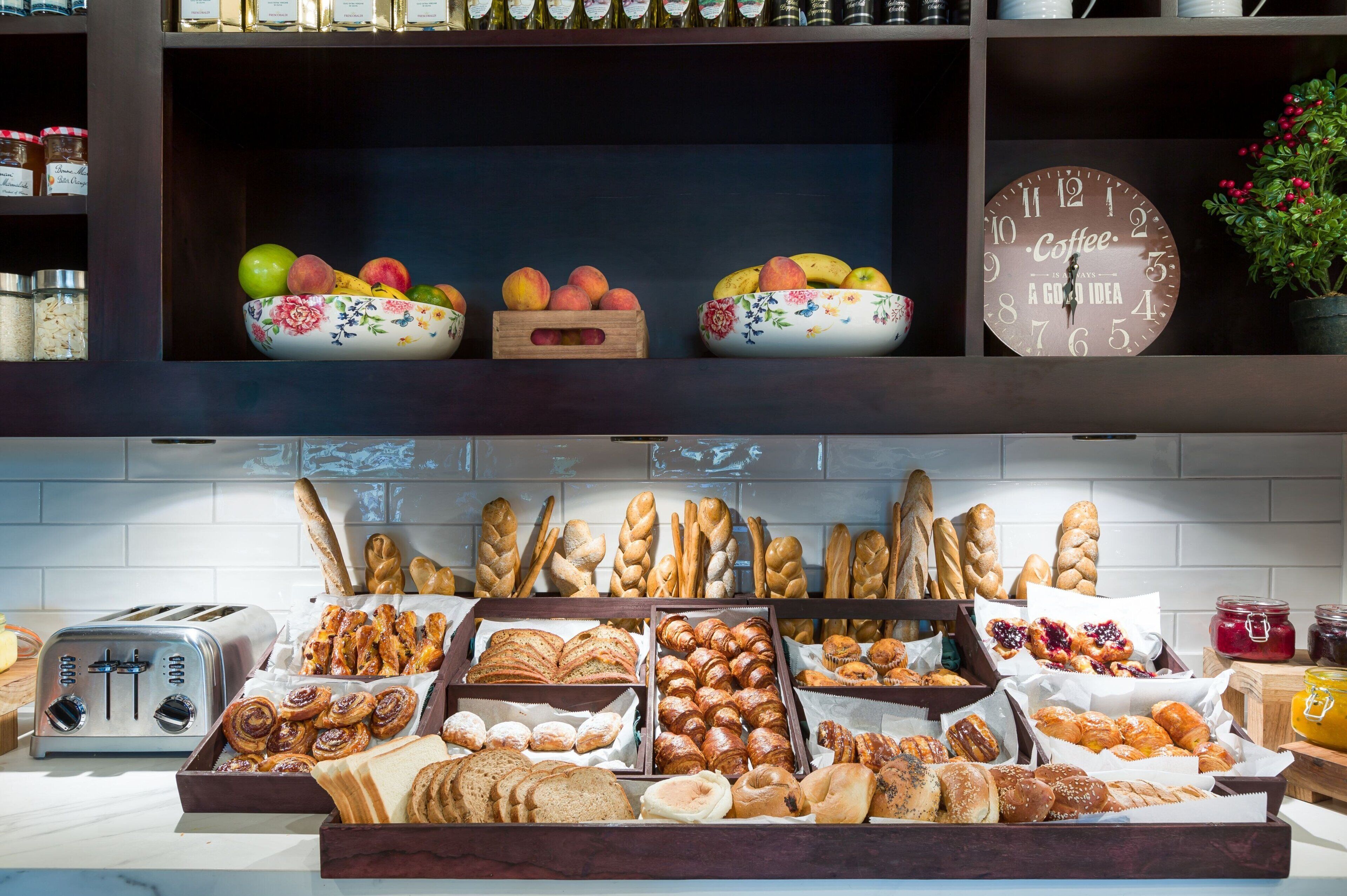A breakfast buffet with various breads, pastries, and fruits.