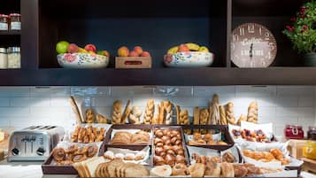 A breakfast buffet with various breads, pastries, and fruits.