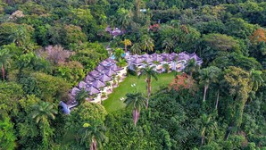 An aerial view of a resort with multiple bungalow-style buildings surrounded by dense tropical vegetation.