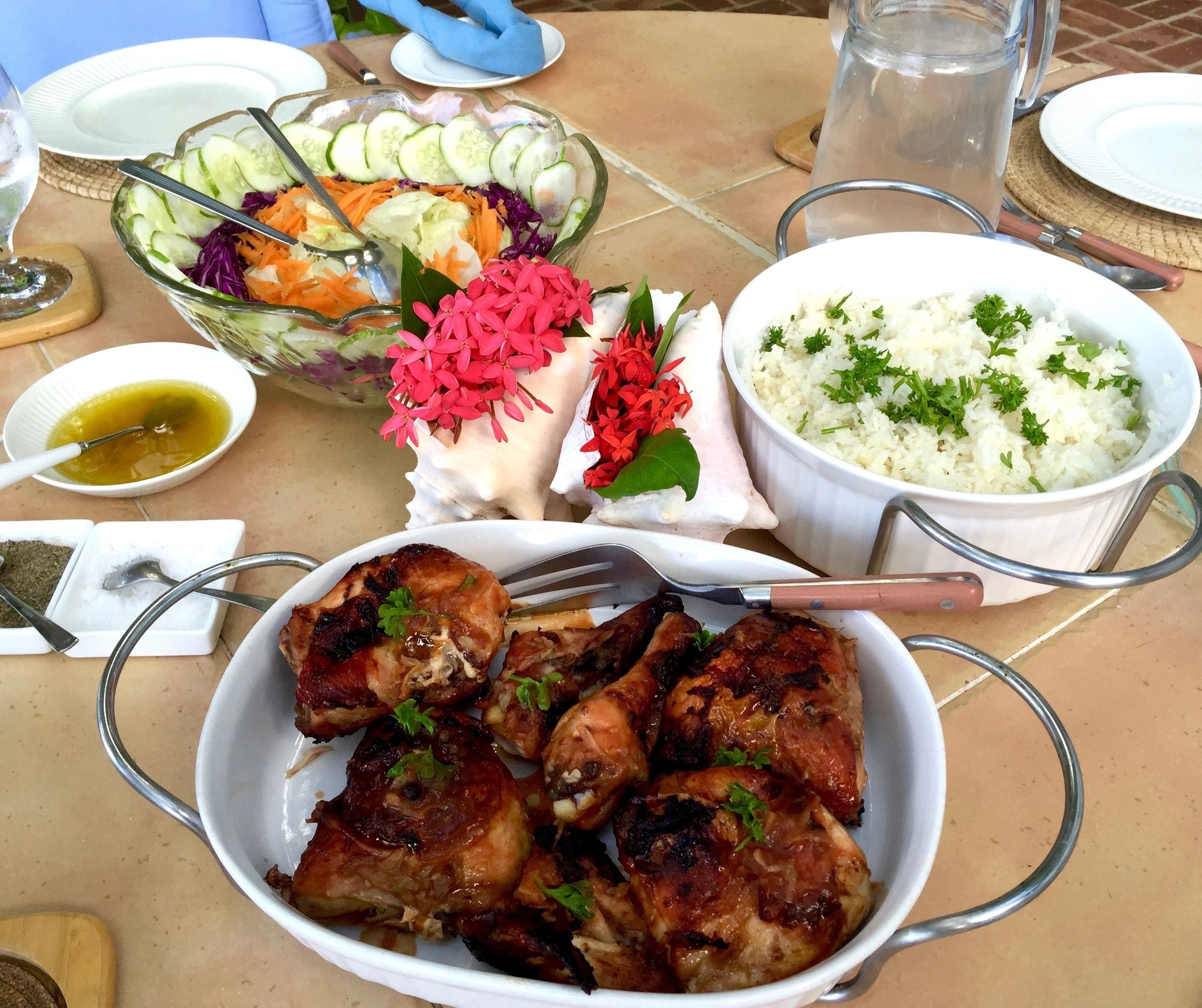 A table set with a salad, rice, grilled chicken, and a small bowl of sauce.
