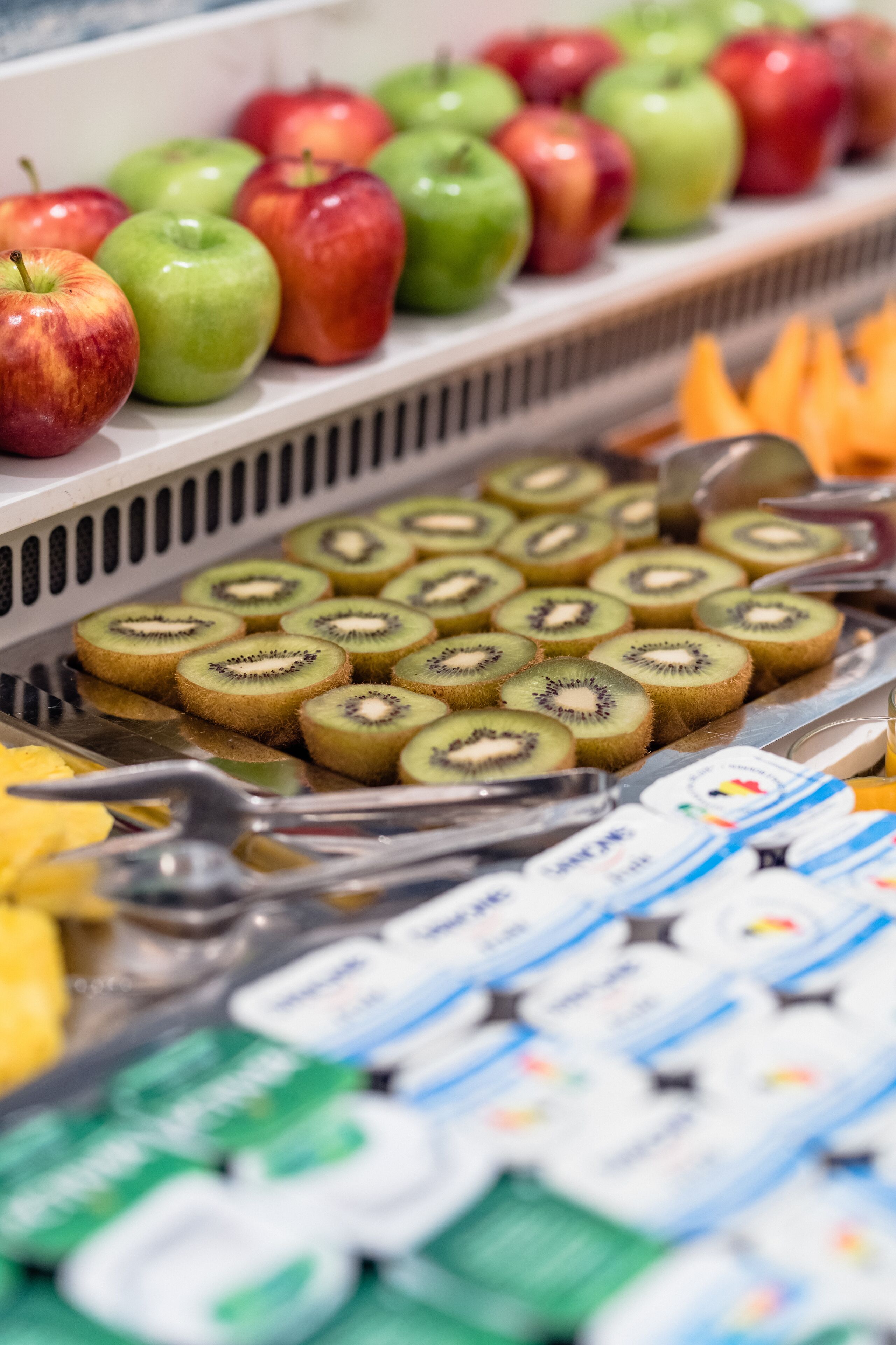 A grocery display with apples, kiwi slices, and dairy products.