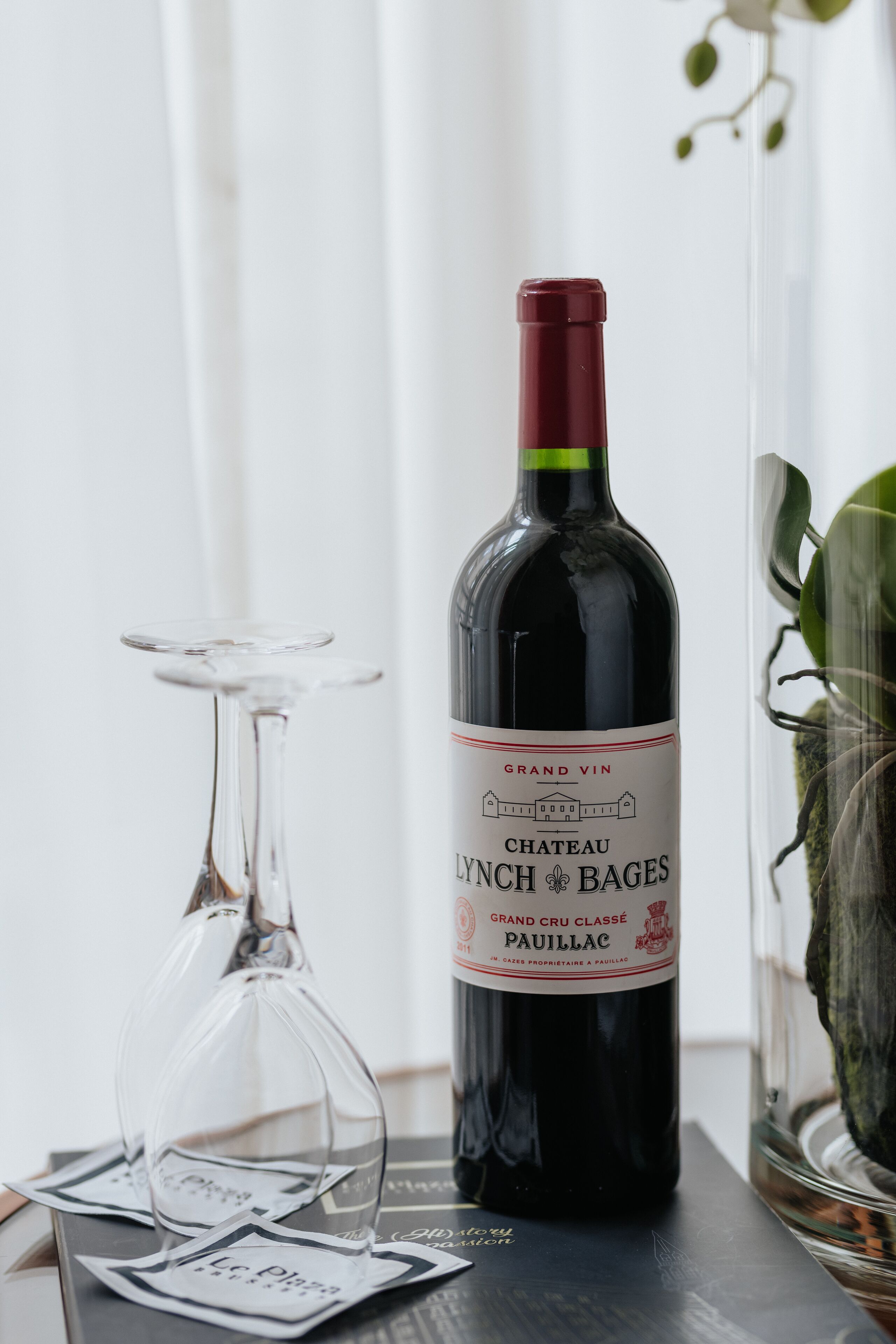 Une bouteille de vin Château Lynch-Bages et un verre à vin sur une table.