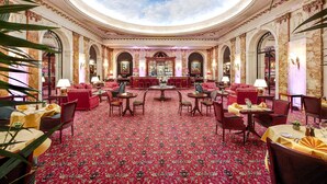 Een statige hotelentree met een hoog plafond, versierde zuilen en een patroonrijk tapijt.