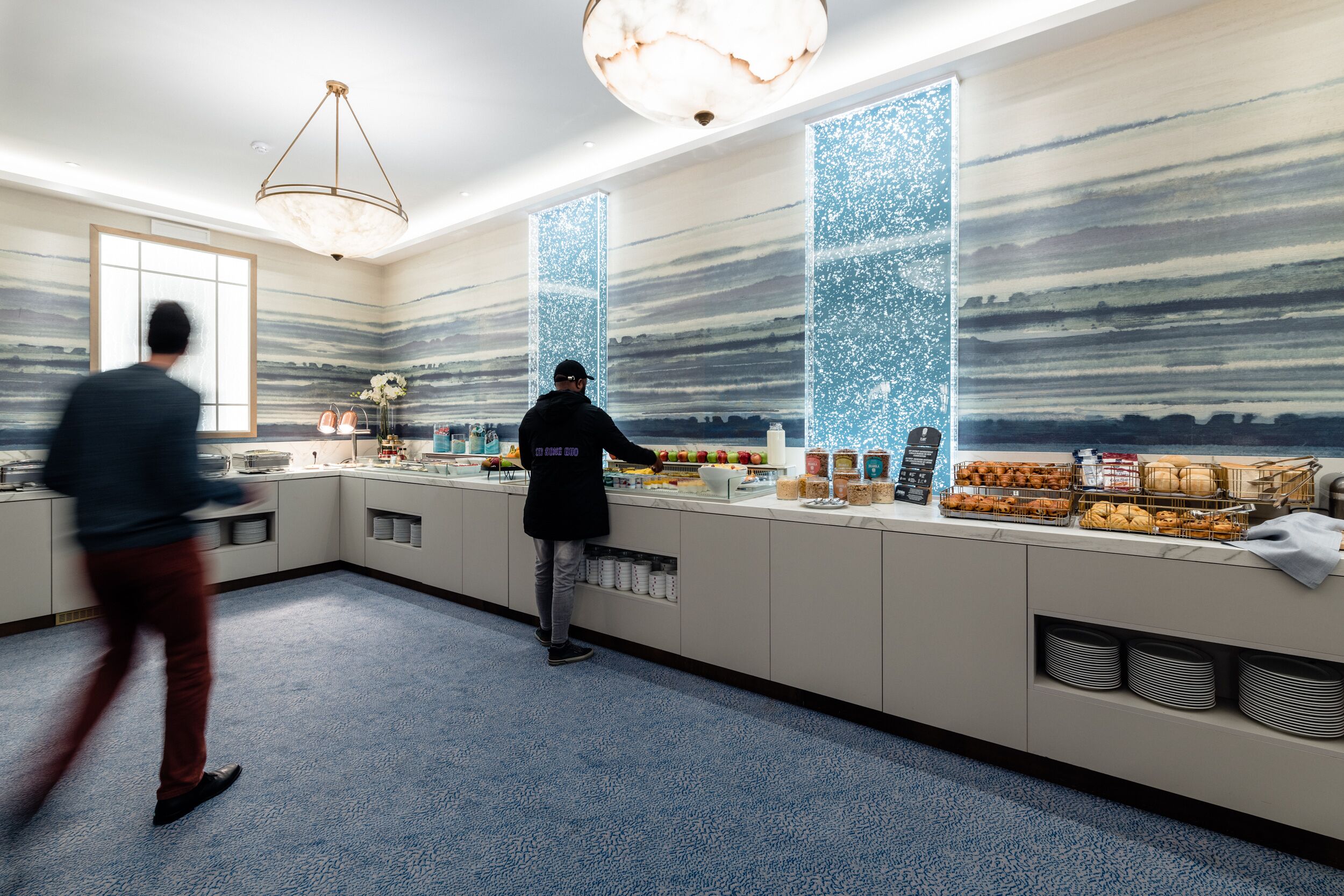 A modern kitchen with a long counter, various food items, and a decorative wall.