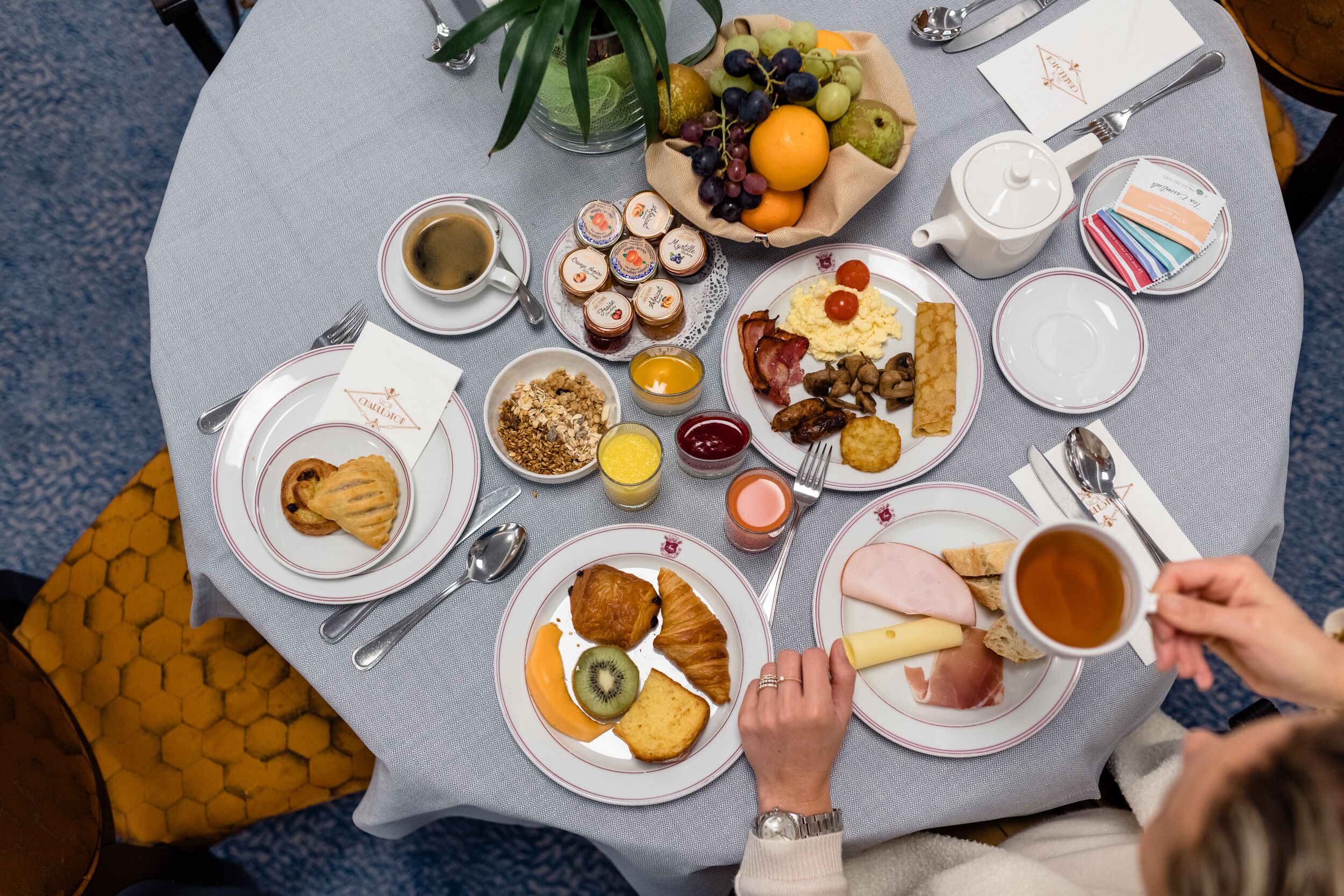 A breakfast table with various food items, including pastries, fruits, and beverages.