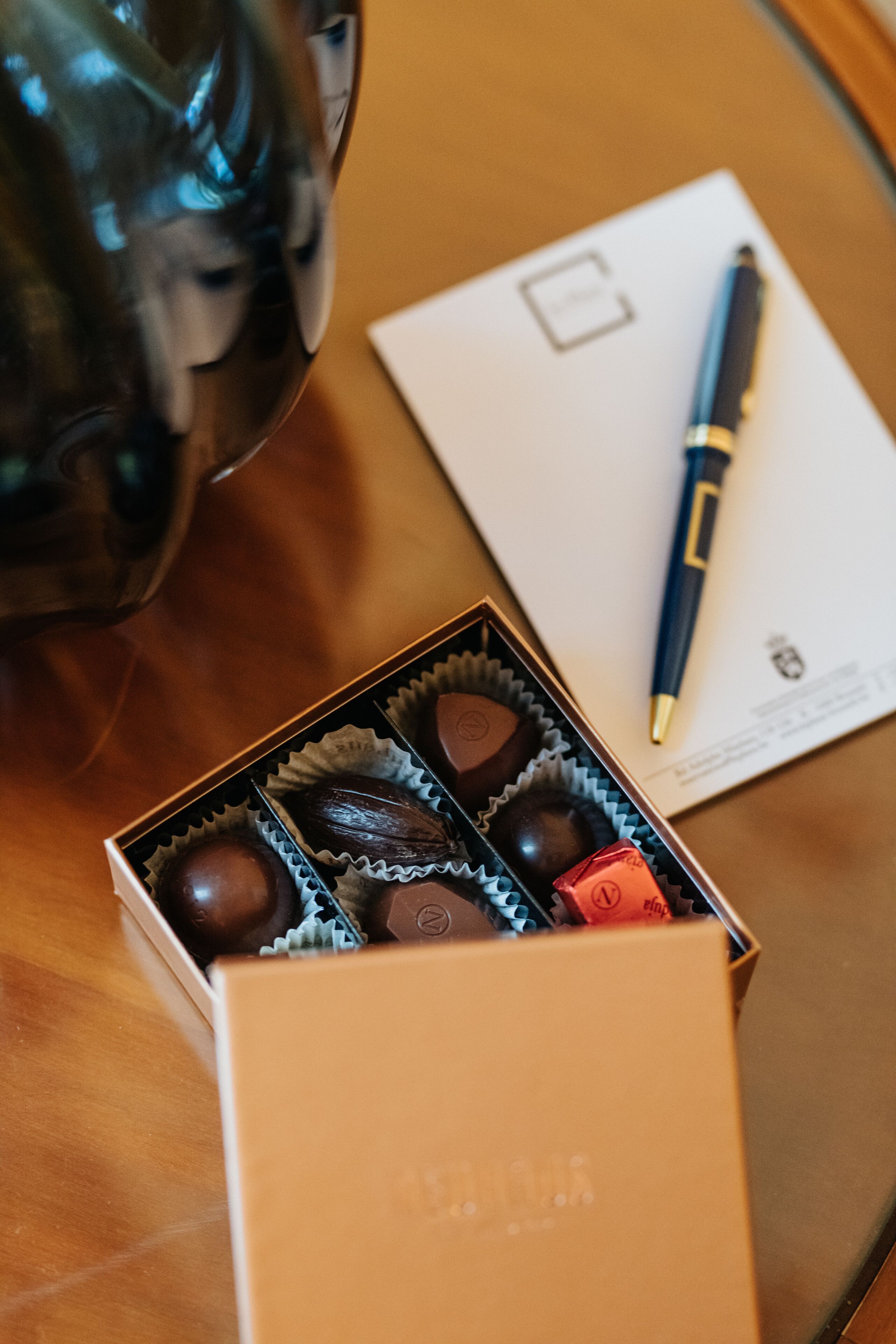 Une boîte de chocolats, un stylo et un document sur une table en bois.