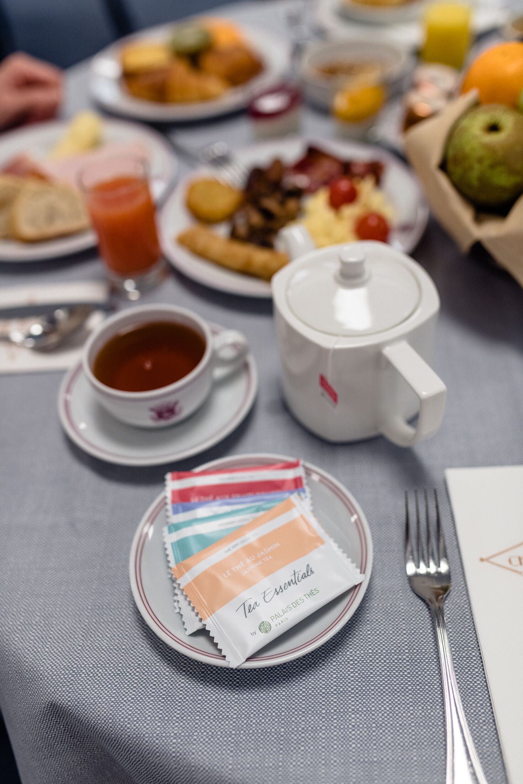 Uma mesa com um bule, xícaras e um saquinho com itens essenciais para o chá.