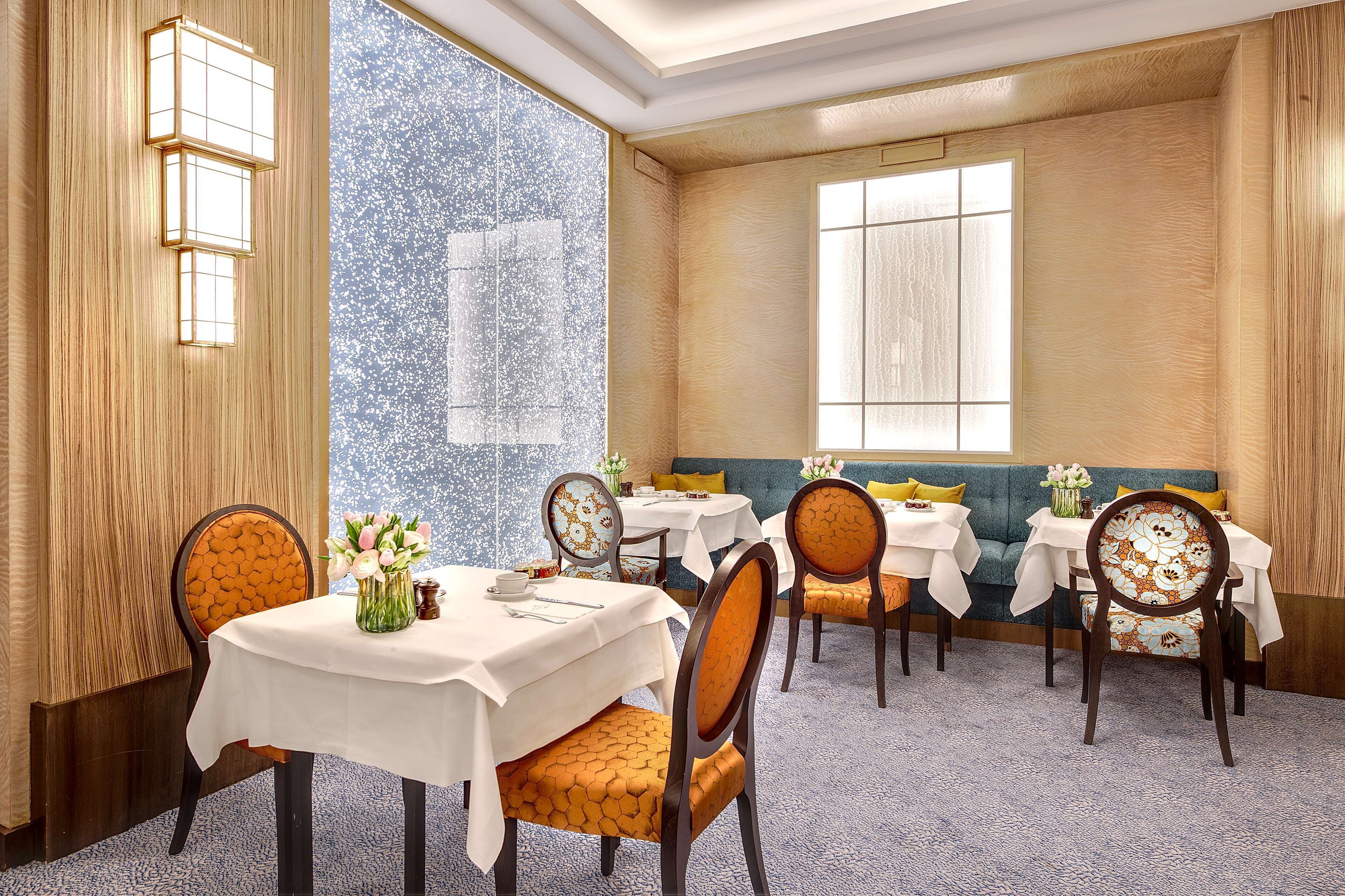 A dining area with multiple tables and chairs, a large window, and a decorative wall.