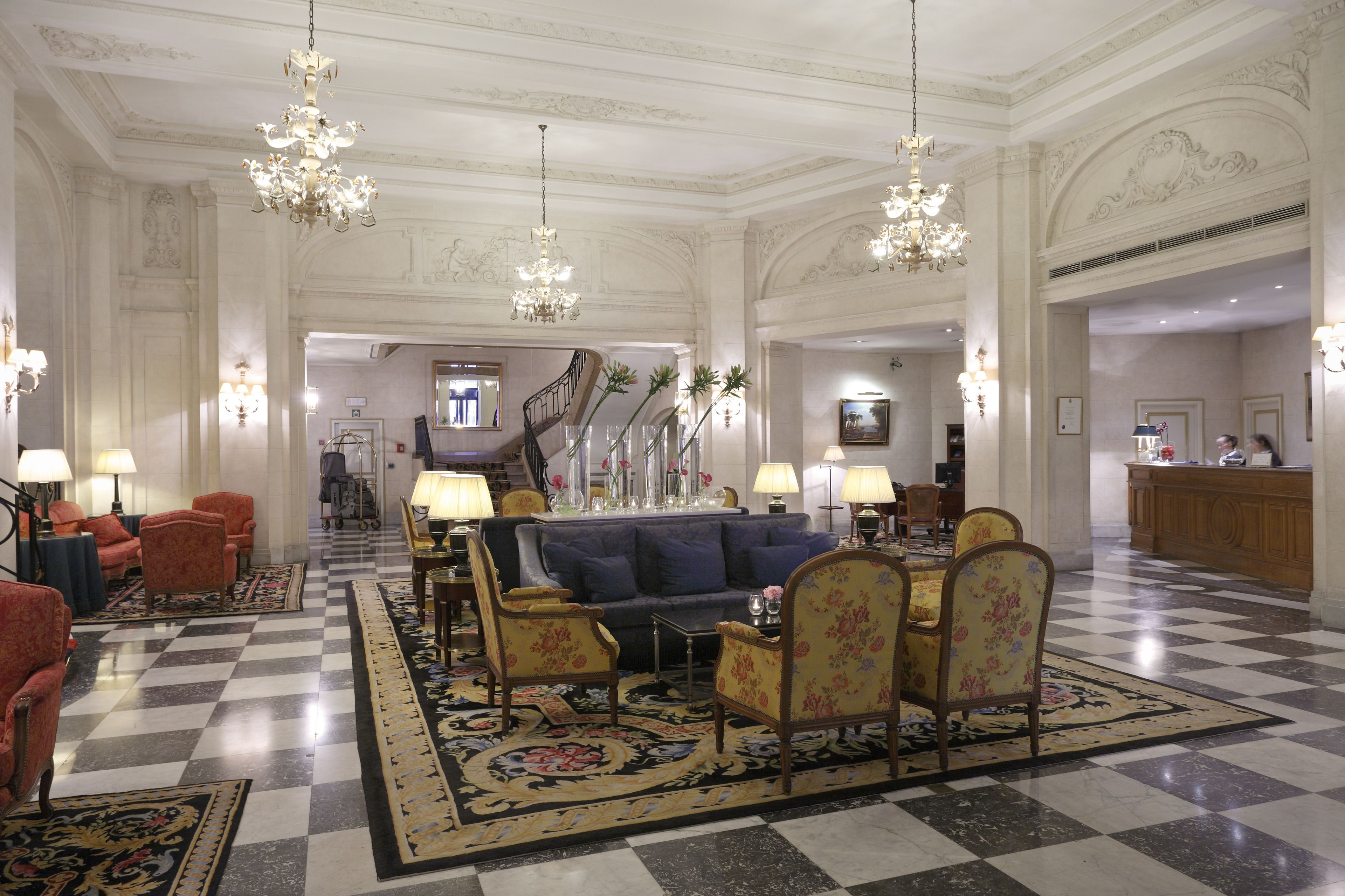 Un lobby imponente con piso a cuadros, candelabros elaborados y mobiliario clásico.